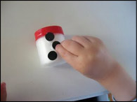 Pendant que les enfants font cela, découpez de petits ronds noirs pour les boutons, un demi-cercle noir pour la bouche et un triangle orange pour le nez.